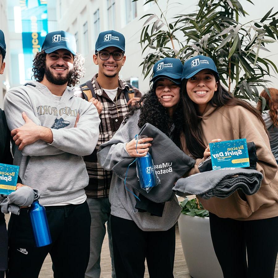 Four students pose in campus center with spirit day swag.